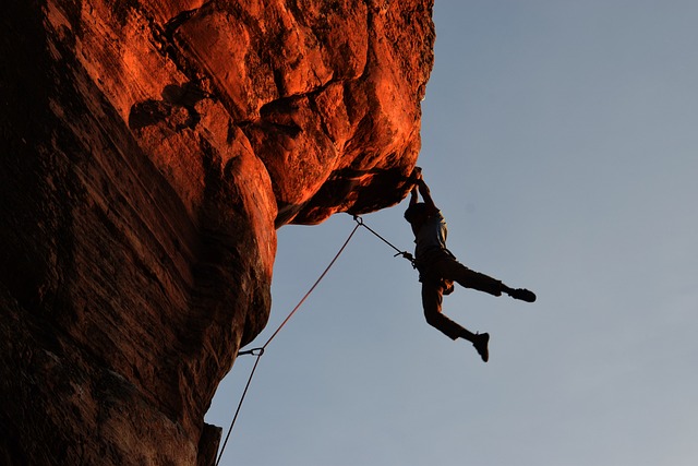 Man lead climbing off a large rock